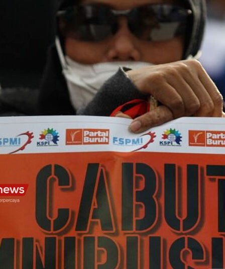 Salah seorang buruh memegang poster tuntutan saat Hari Buruh Internasional