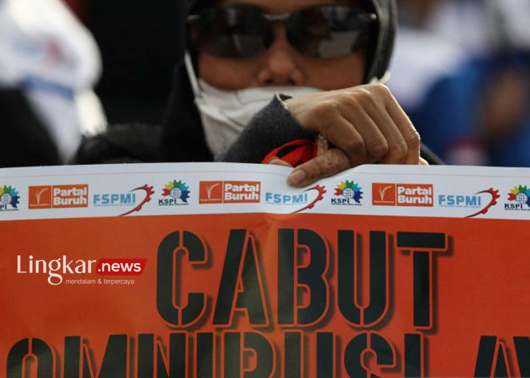Salah seorang buruh memegang poster tuntutan saat Hari Buruh Internasional